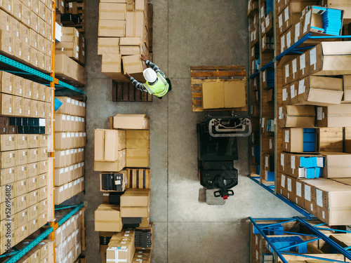 Top view of a warehouse worker moving package boxes in a logistics centre photo