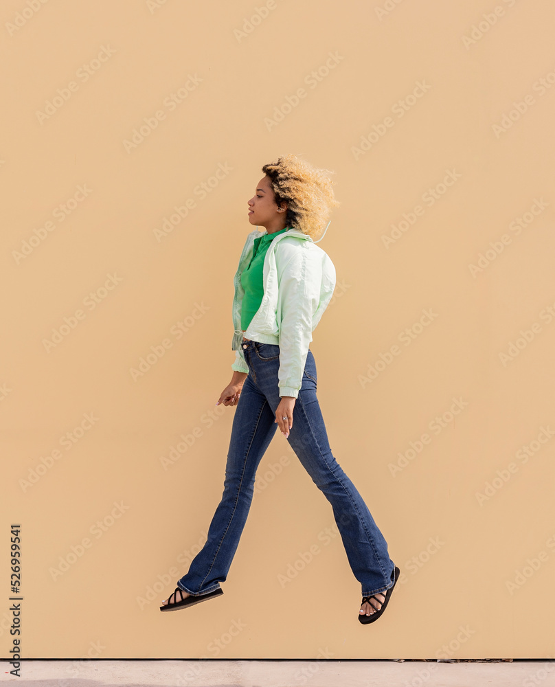Young woman jumping in front of wall Young woman jumping in front of wall