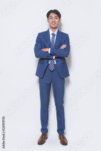 Full body young businessman wearing suit, blue shirt with tie , arms crossed standing in studio