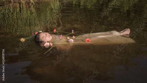 woman in long white dress floating in water of lake with flowers like Ophelia photo