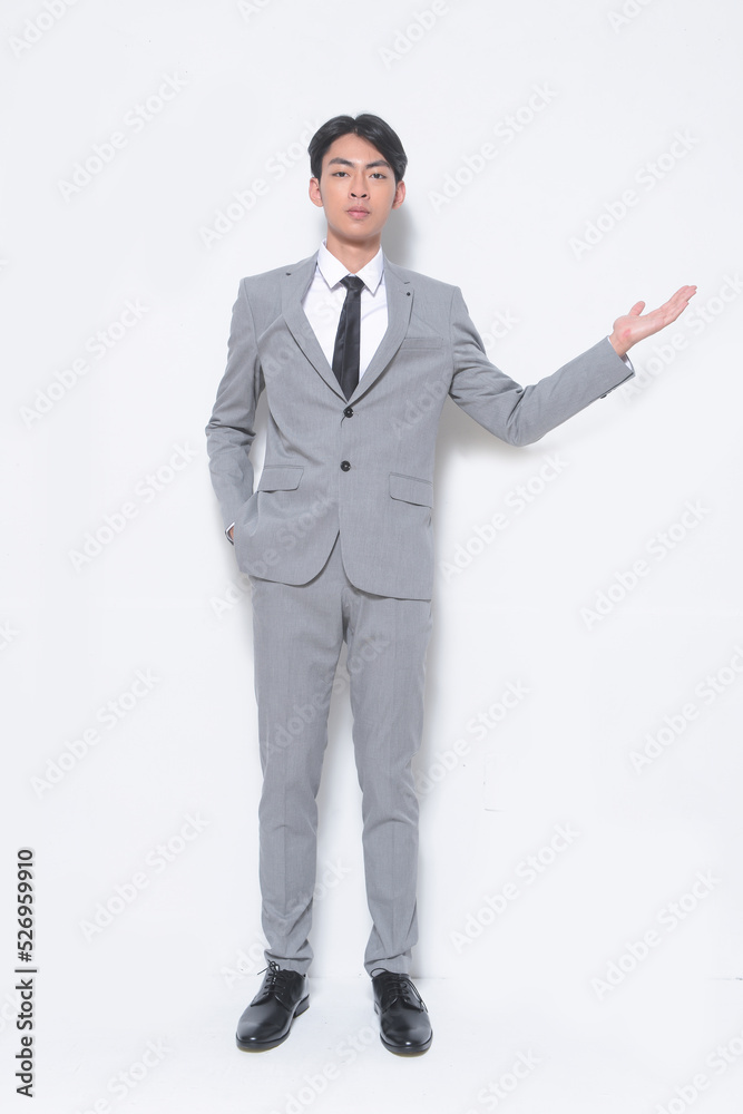 Full body young businessman wearing gray suit, white shirt ,black, tie ,welcome, gesture standing in studio Full body young businessman wearing gray suit, white shirt ,black, tie ,welcome, gesture standing in studio