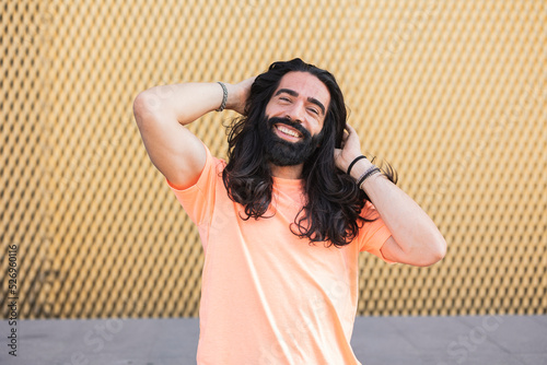 Happy bearded man standing with hands in hair