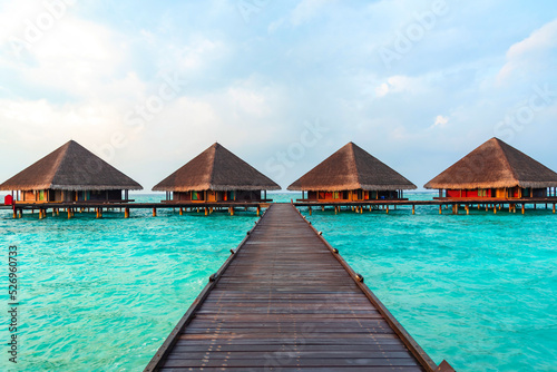 view of the water villas at sunrise in the Maldives, the concept of luxury travel © klavdiyav