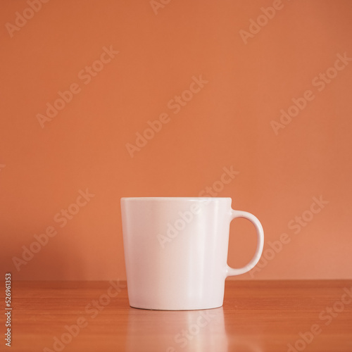 Pink ceramic coffee cup on wood table with brown background