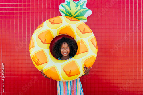 Cute girl holding inflatable ring standing in front of wall photo