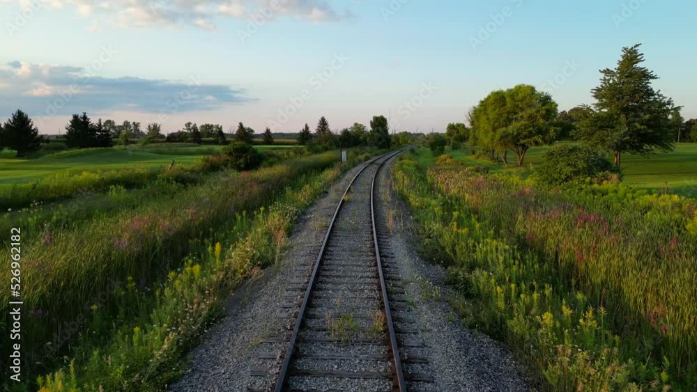 Drone flight along railroad track through scenic lush green countryside Drone flight along railroad track through scenic lush green countryside