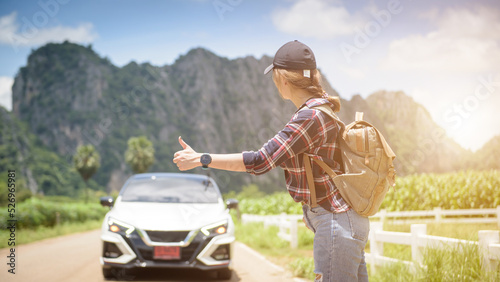 Pick me up. Backpacking lady on the side of the road. Woman trying to stop. Thumbs up for hitchhiking. One of the cheapest ways to travel
