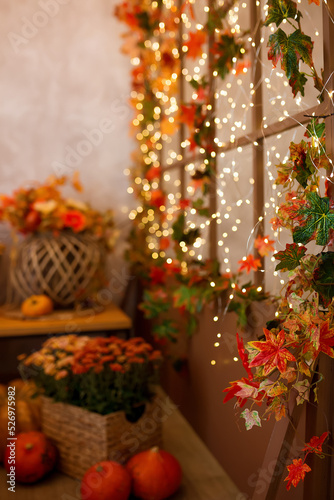 Orange pumpkin with a lovely autumn flower composition on the background of yellow and orange fallen leaves