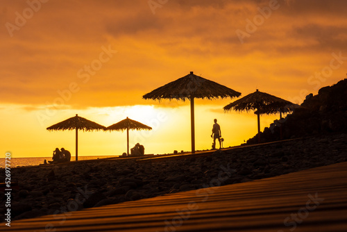 Orange sunset on the umbrellas at Ponta do Sol beach, Madeira. Portugal