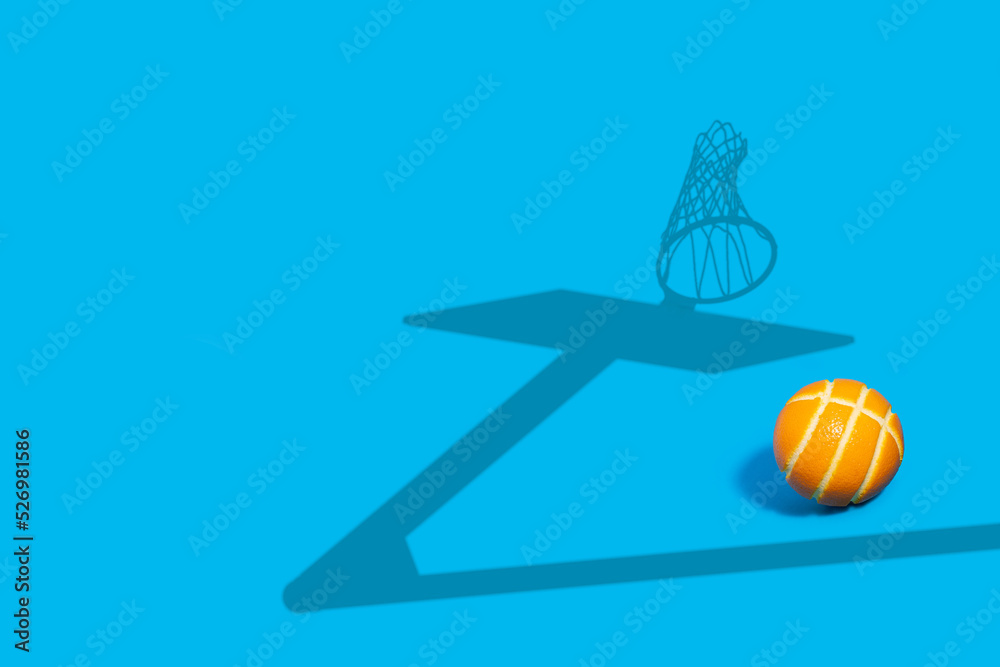 Orange as a basketball on a blue background with a basketball hoop shadow.