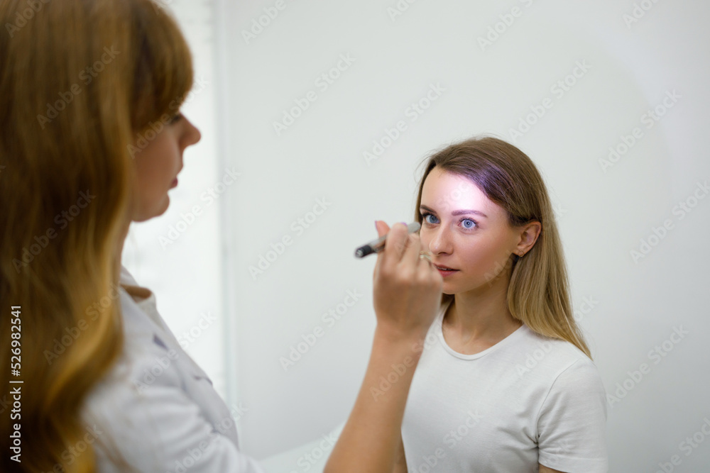 Young woman in neurologist appointment. Female doctor checks eyes reflexes with flashlight Young woman in neurologist appointment. Female doctor checks eyes reflexes with flashlight