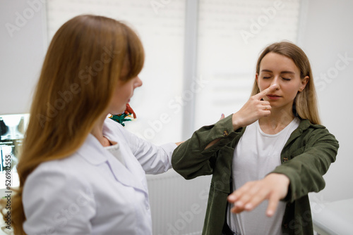 Картината върху платно Woman with closed eyes touch nose with fingertip during physical examination