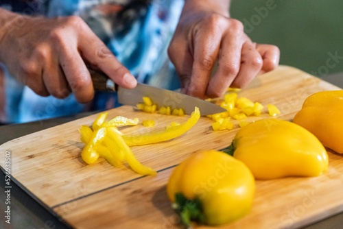 cutting yellow peppers on a wooden board, Majorca, Balearic Islands, Spain