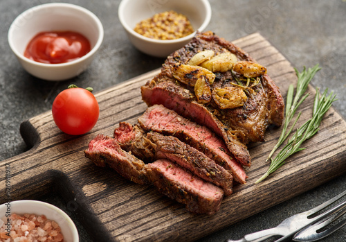 Medium rare Ribeye steak or beef steak on the wooden tray with herbs