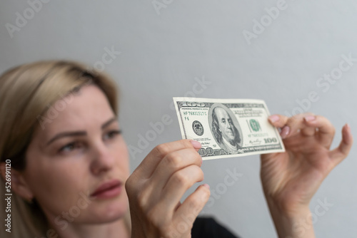 Woman holding dollar bill and looking at it with watermarks closeup. Counterfeiting money concept.