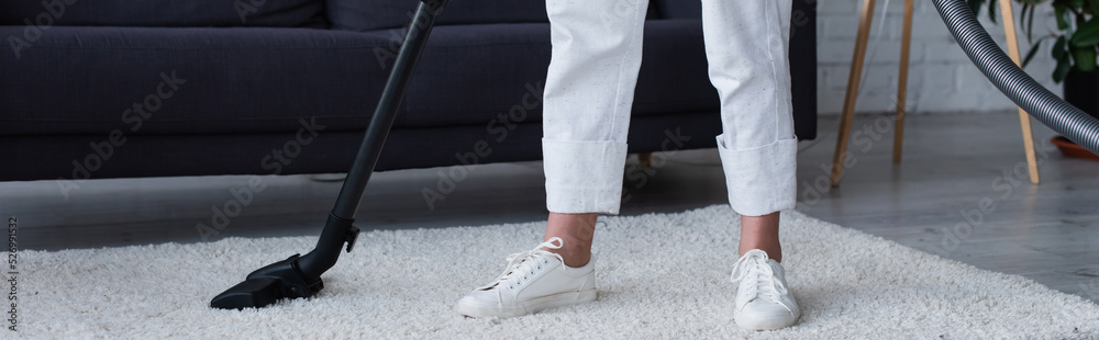 Cropped view of woman cleaning carpet with vacuum cleaner at home, banner. Cropped view of woman cleaning carpet with vacuum cleaner at home, banner.