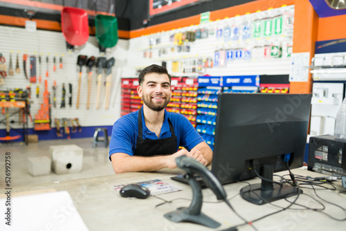 Happy hardware store employee at the computer desk at work photo