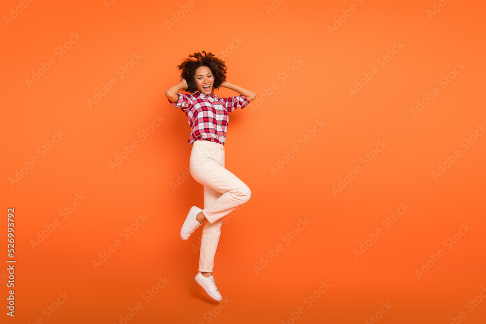 Full length body size view of attractive cheery girl jumping having fun rest isolated on bright orange color background