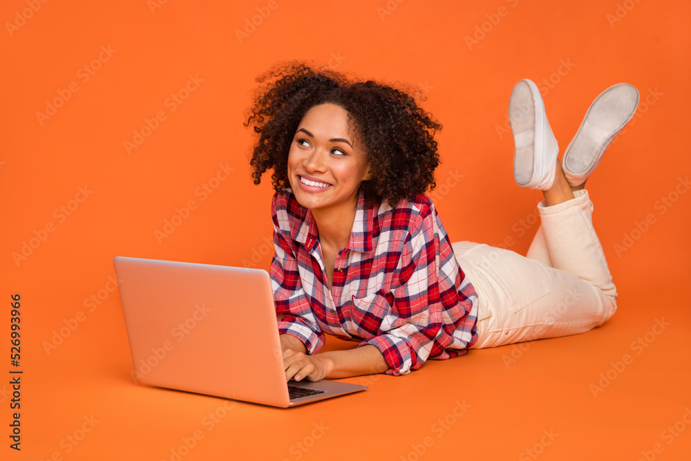 Photo of shiny thinking lady dressed checkered shirt chatting gadget looking empty space isolated orange color background Photo of shiny thinking lady dressed checkered shirt chatting gadget looking empty space isolated orange color background