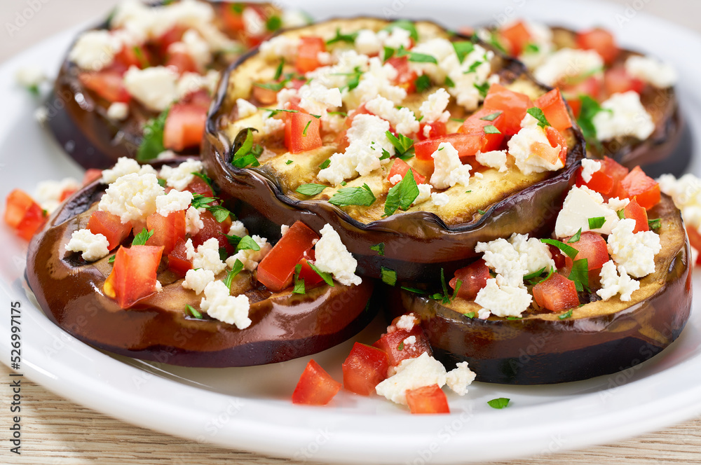 Salad with grilled eggplant, feta and tomatoes on a white plate,selective focus. Salad with grilled eggplant, feta and tomatoes on a white plate,selective focus.