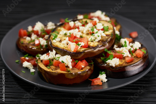 Salad with grilled eggplant, feta and tomatoes on a black plate,selective focus.