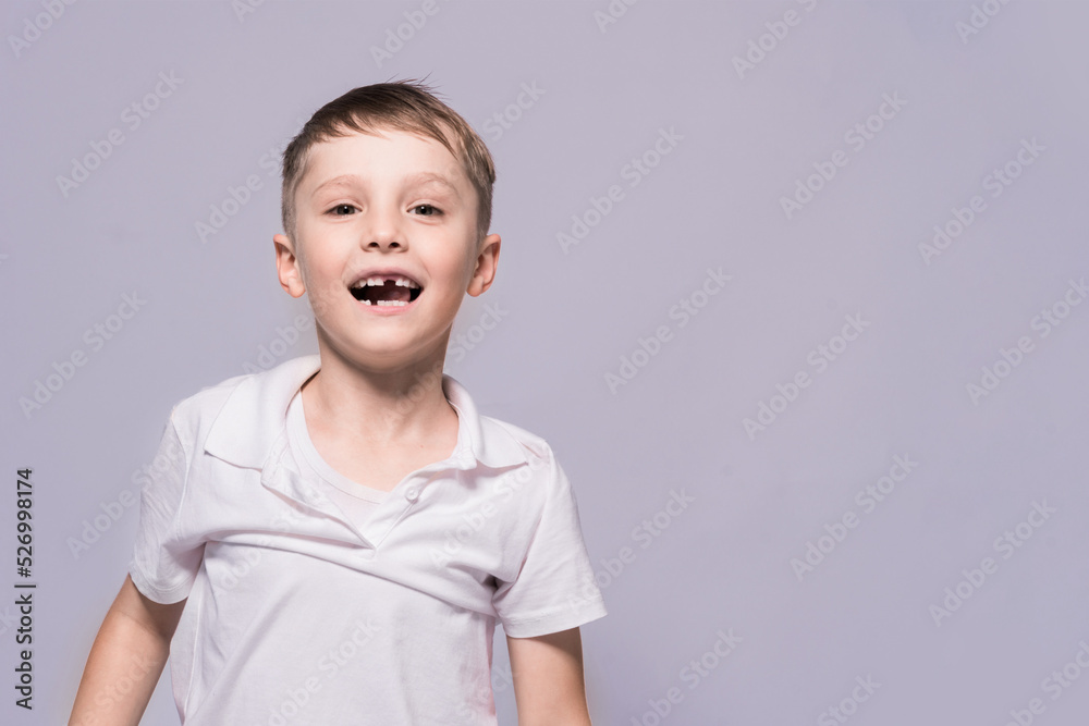 Toothless little boy in a white t-shirt is smiling. Posing in the studio