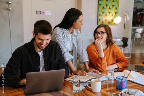 Multiracial young colleagues discussing project while working in office photo