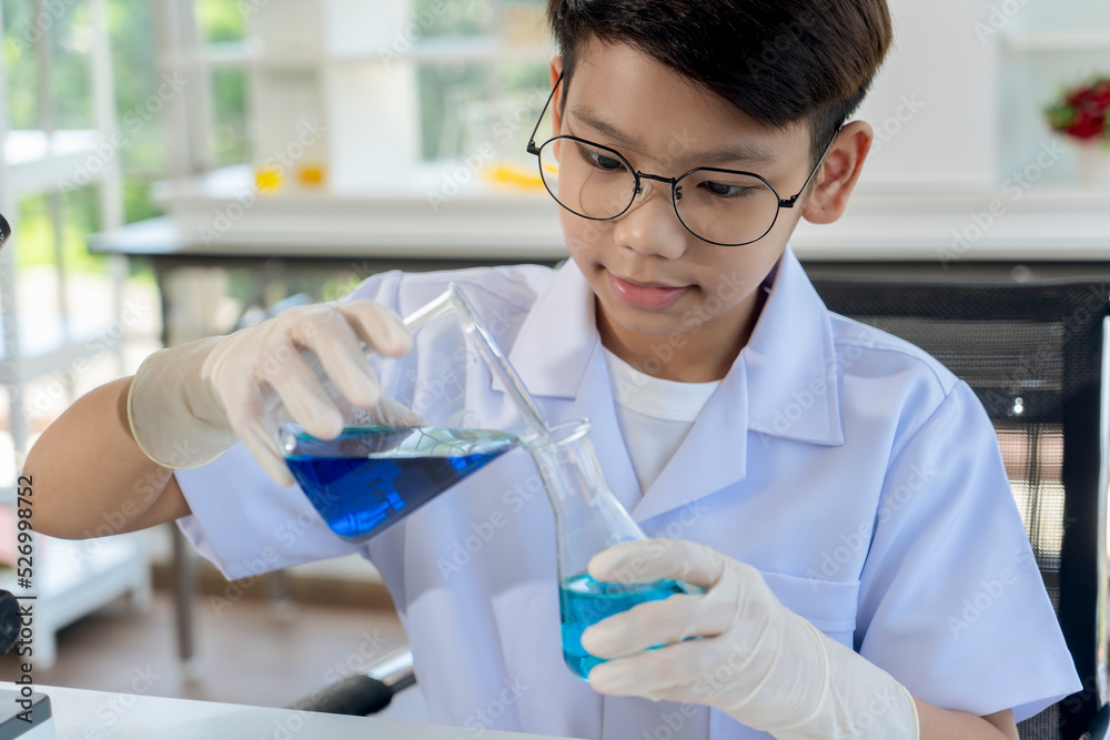Asian boy researches blue liquid in chemistry lesson at laboratory Asian boy researches blue liquid in chemistry lesson at laboratory
