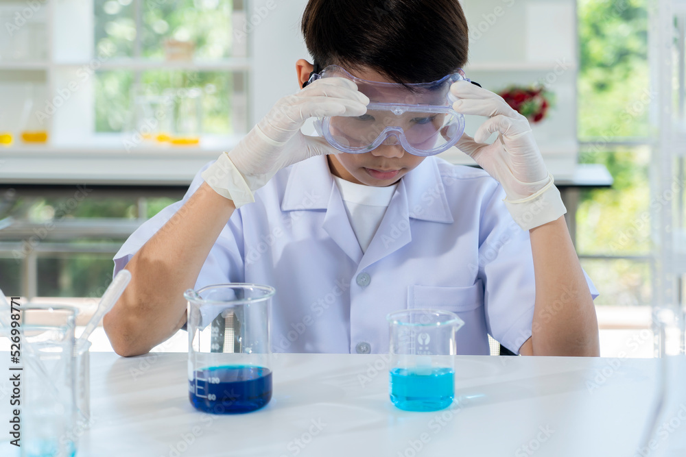 Asian boy use glass bulb drop dark blue in beaker Asian boy use glass bulb drop dark blue in beaker