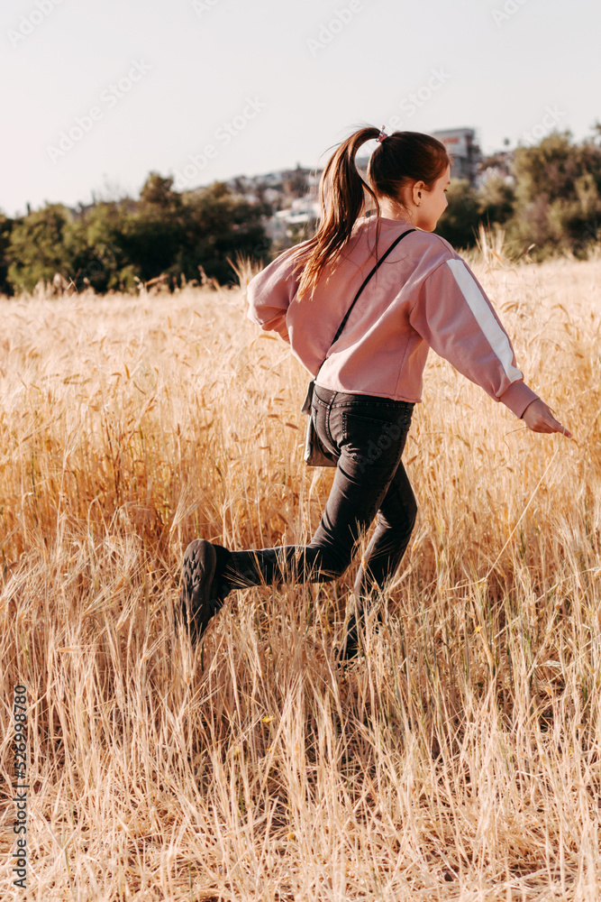 Little girl having fun in wheat rural field, running, enjoying freedom.