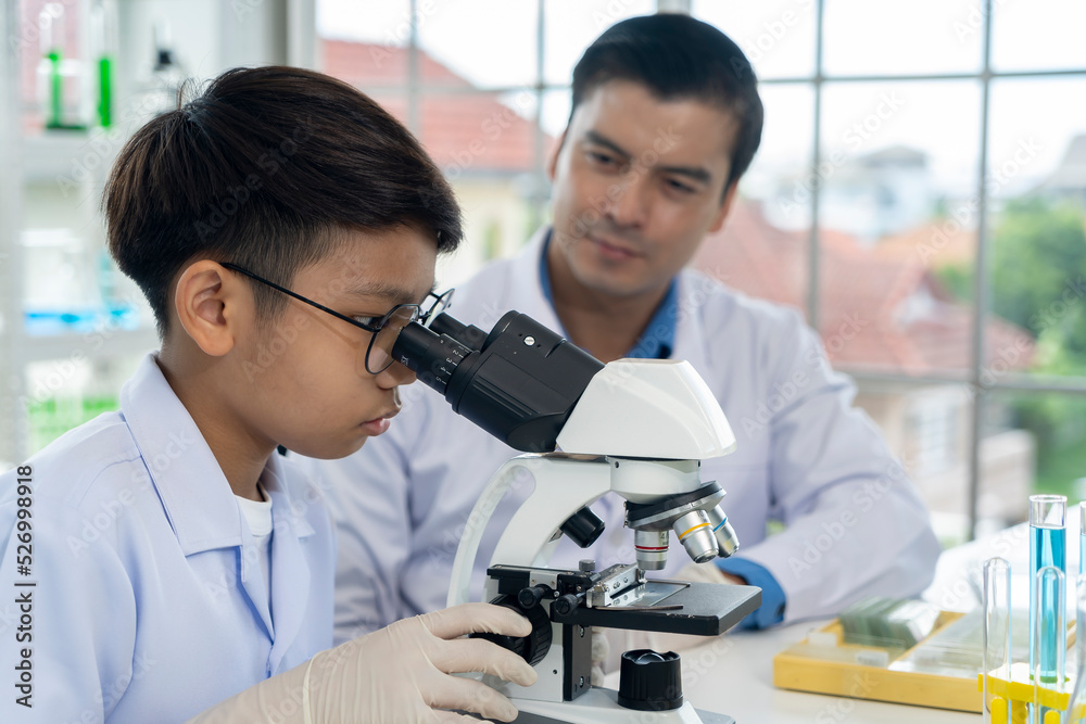 Young teacher and boy use microscope in science class at laboratory Young teacher and boy use microscope in science class at laboratory