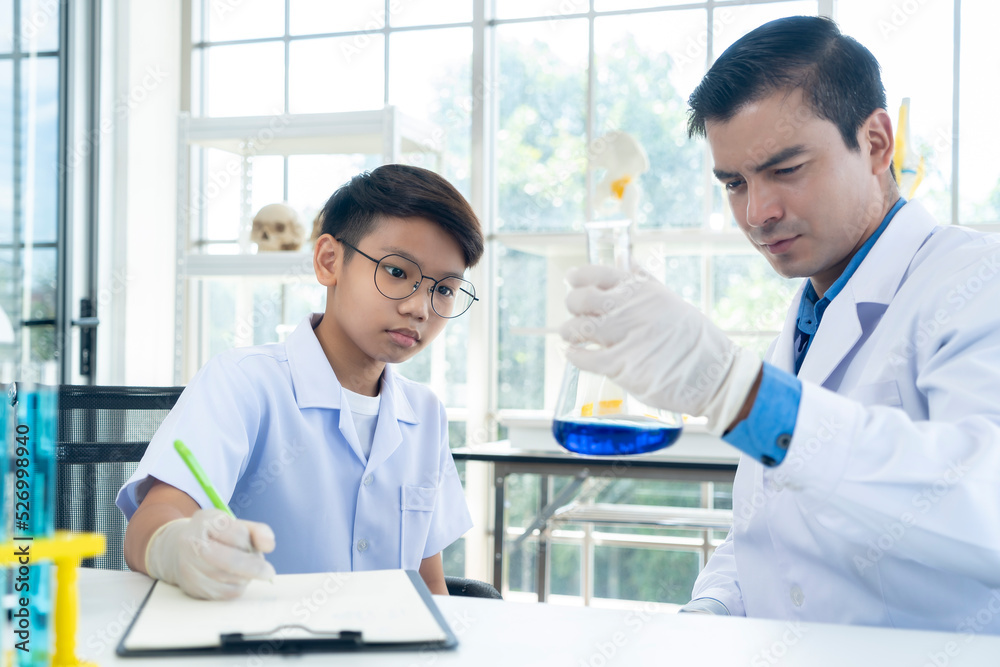 Young teacher and student boy use microscope in science class at laboratory Young teacher and student boy use microscope in science class at laboratory