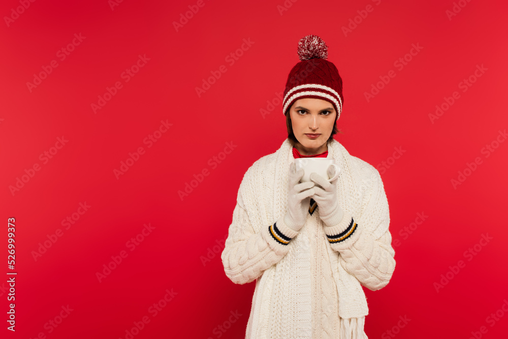 Brunette woman in warm clothes holding cup isolated on red. Brunette woman in warm clothes holding cup isolated on red.
