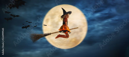 Fotografija child flies as a witch to helloween with the moon in the background