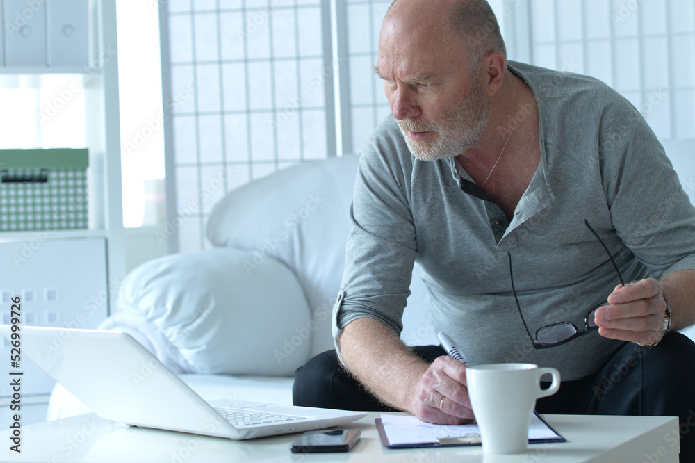Senior businessman using laptop on sofa at home Senior businessman using laptop on sofa at home