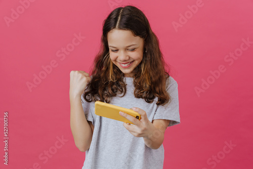 White preteen girl gesturing while playing online game on cellphone
