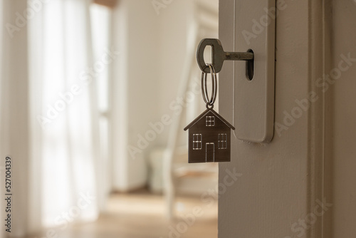 Open door to a new home with key and home shaped keychain. Mortgage, investment, real estate, property and new home concept © dechevm