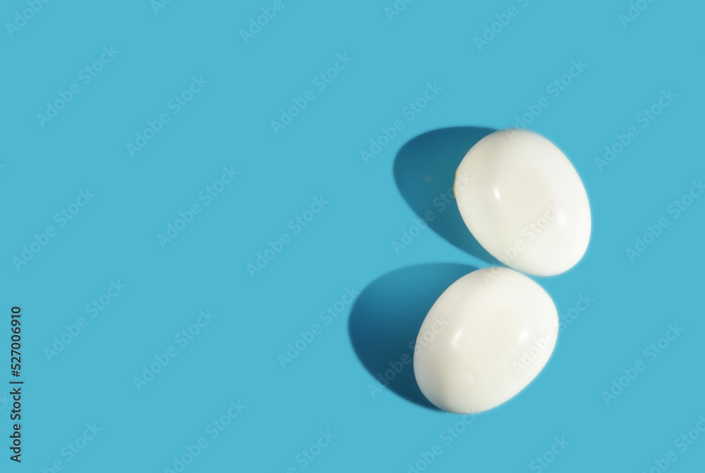 Two boiled eggs with shadow on blue background with sunlight. Copy space concept and torether idea