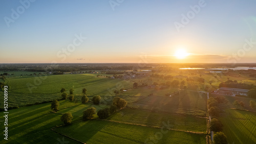 Aerial Drone Shot of a beautiful Green and Yellow Agricultural Plantations Bordering with Wild Forests in Belgium  Europe with the golden rays of sun creating a magical blanket over the green