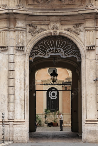 Sculpted Building Entrance with Lantern and Standing Man in Rome, Italy
