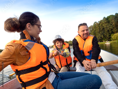 Friendly caucasian family floating on kayak with paddles. Concept of family rest, leisure and weekend at nature. father and daughter wearing life vests. autumn sunny day.Selective focus