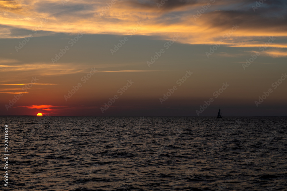 samotny jacht płynący po Zatoce Gdańskiej na tle zachodzącego słońca