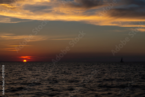 żaglówka płynąca w stronę zachodzącego słońca © Kamil_k2p