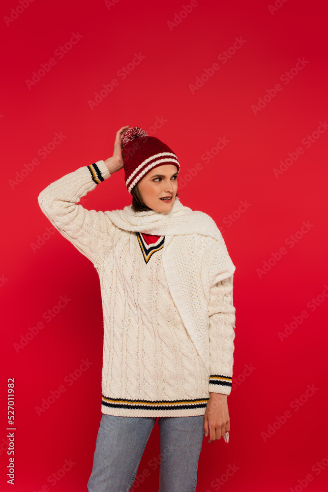 Smiling woman in hat and knitted clothes looking away isolated on red. Smiling woman in hat and knitted clothes looking away isolated on red.