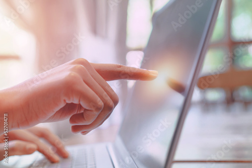 hand touching laptop screen with indoor background,cyberspace and technology concept