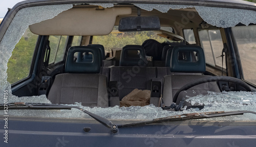 close-up of the broken windshield of the car. An old abandoned car with a broken windshield and windows on the passenger seat. Shards of broken glass.