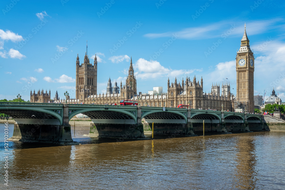 Red buses on Westminster bridge over river Thames, Big Ben and the houses of parliament in London, UK