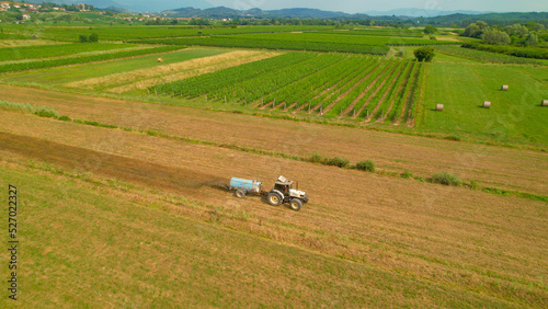 Konstfotografi AERIAL: White tractor with slurry spreader fertilizing arable land in autumn