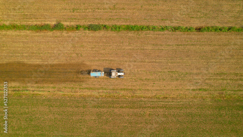 AERIAL, TOP DOWN: Farm tractor spreading manure on arable land in autumn season