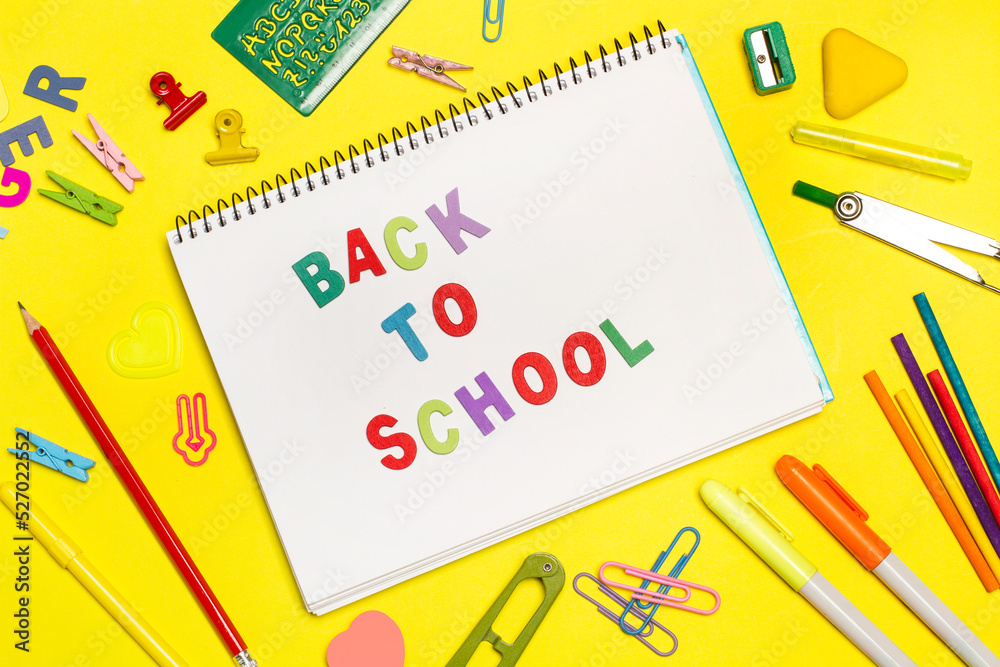 Concepto de vuelta al colegio. Cuaderno abierto con útiles escolares sobre un fondo amarillo brillante. Vista superior y de cerca Concepto de vuelta al colegio. Cuaderno abierto con útiles escolares sobre un fondo amarillo brillante. Vista superior y de cerca